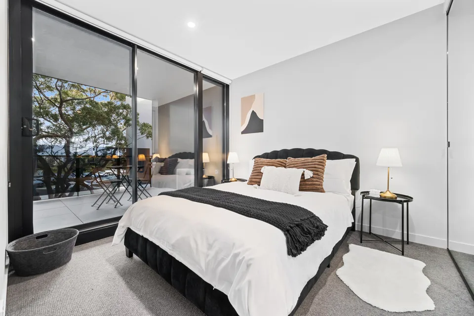 First bedroom with large windows and a queen bed