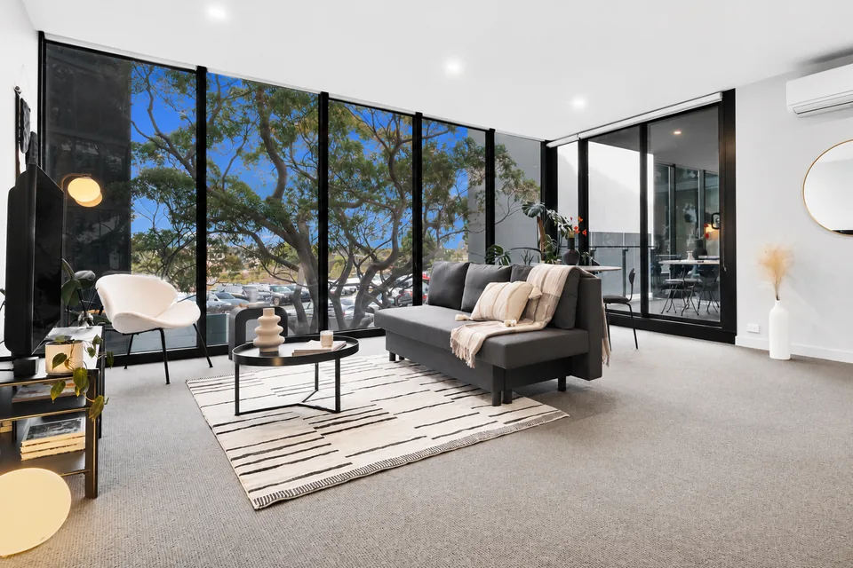 Wide view of the living room with sofa, lounge chair and balcony doors