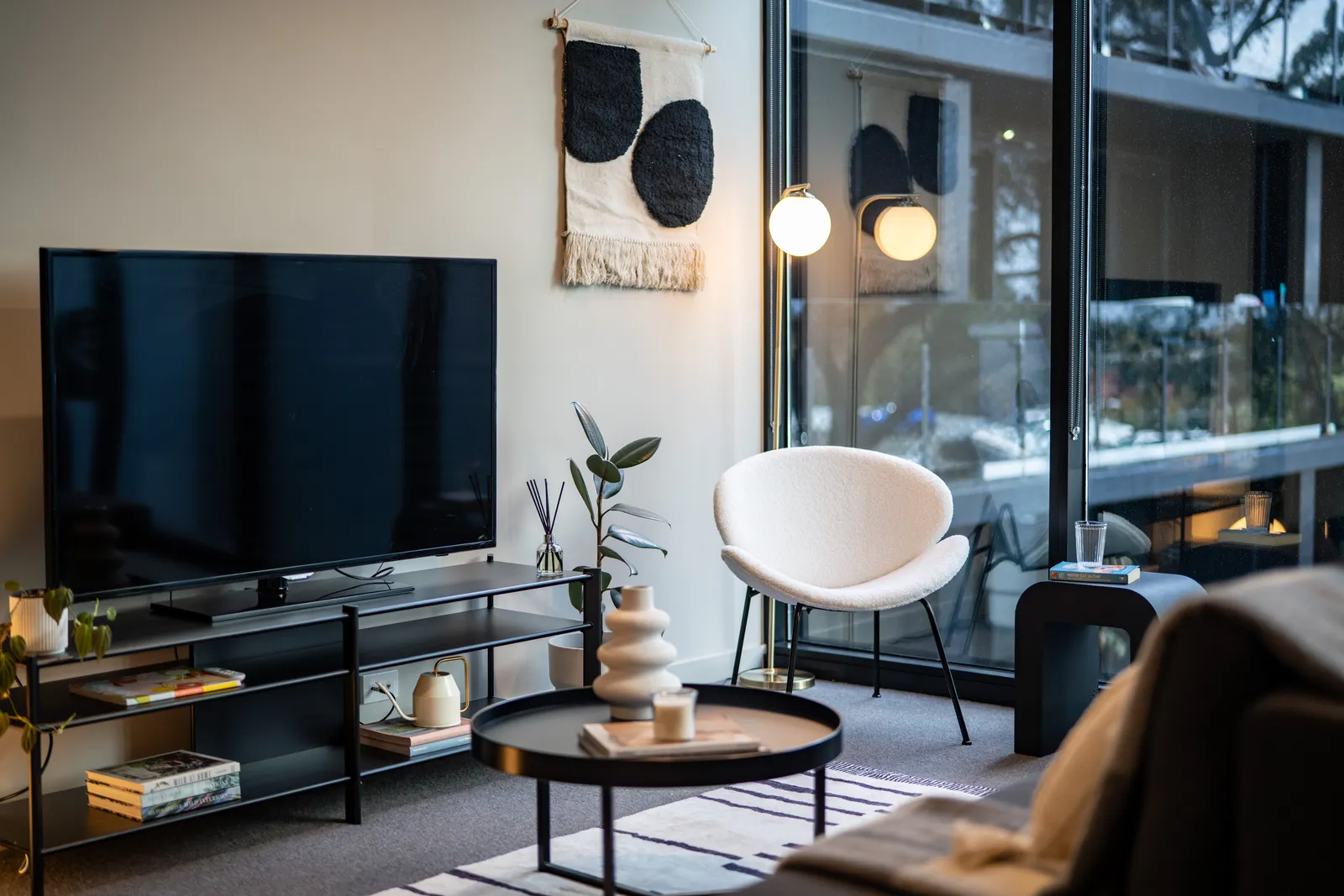 Living room with television, lounge chair and floor-to-ceiling windows